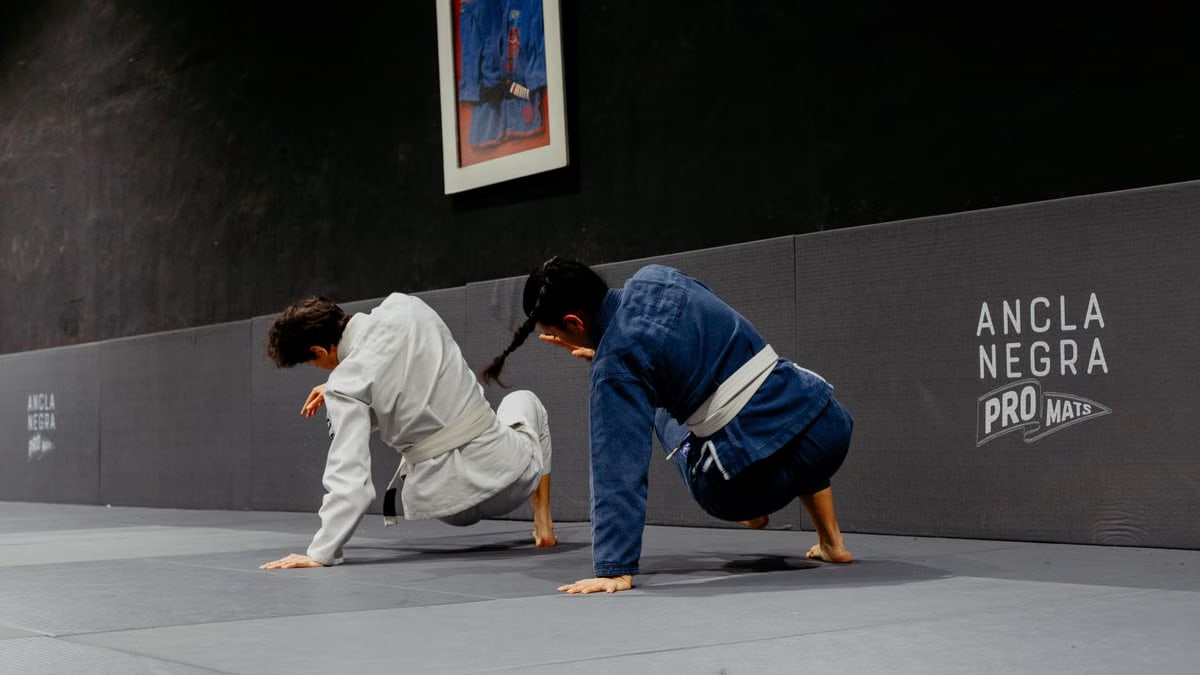 Two martial artists practice jiu-jitsu techniques indoors in Buenos Aires dojo.